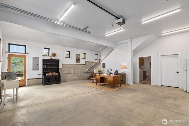 garage featuring a garage door opener, electric panel, and freestanding refrigerator
