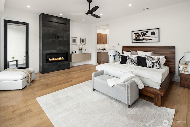 422 98th Ave NE, Bellevue, WA 98004 - bedroom featuring recessed lighting, visible vents, a tiled fireplace, and light wood-style floors