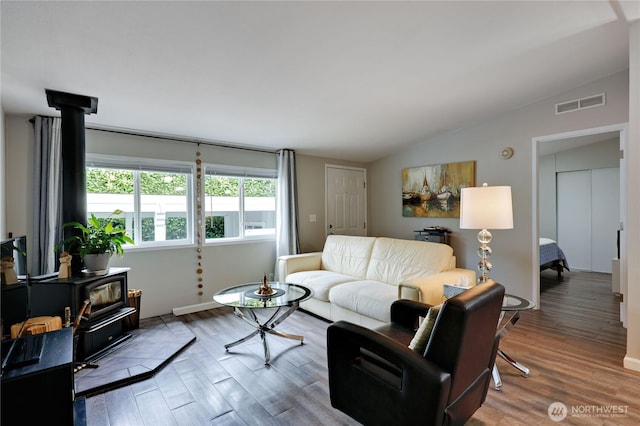 8760 State Highway 303 NE Unit C, Bremerton, WA 98311 - living area featuring visible vents, a wood stove, lofted ceiling, and wood finished floors