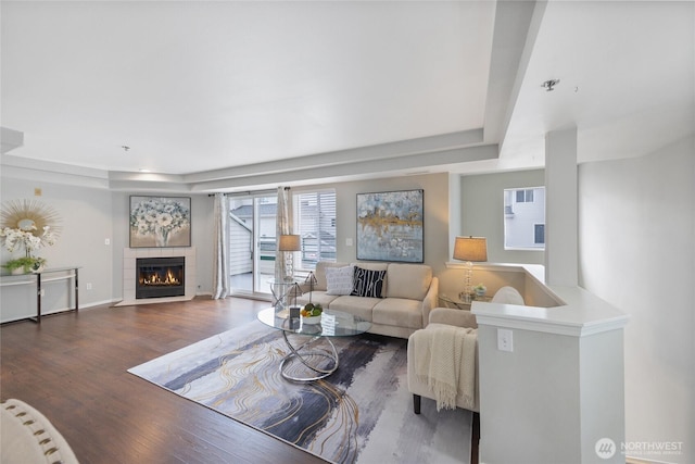 living room featuring baseboards, wood finished floors, a raised ceiling, and a tile fireplace