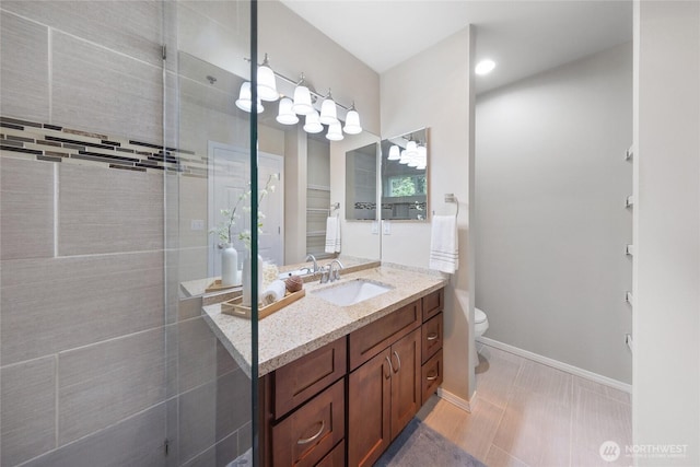 full bath featuring vanity, baseboards, a tile shower, and toilet