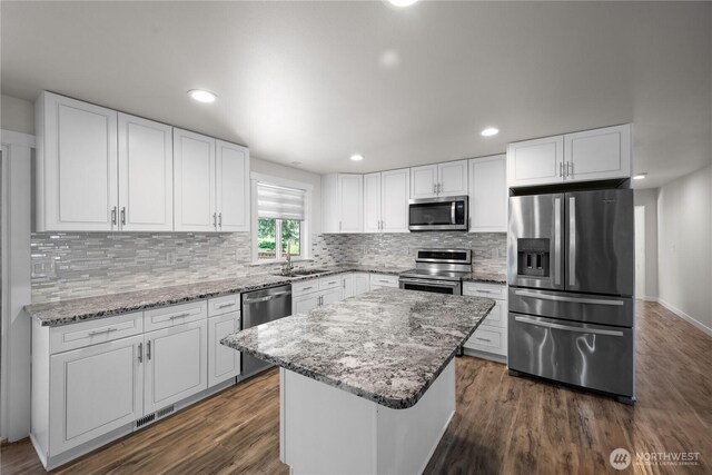 kitchen with a kitchen island, stainless steel appliances, dark wood-style floors, and tasteful backsplash