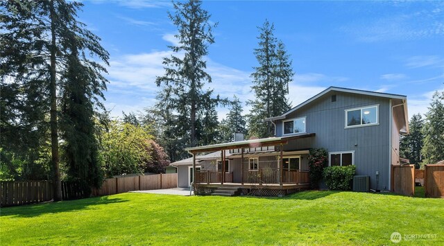 back of property with a lawn, a wooden deck, and a fenced backyard