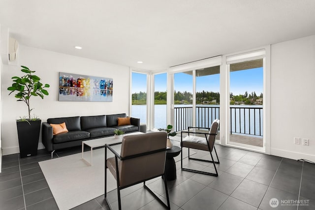 living area featuring expansive windows, baseboards, a water view, and dark tile patterned flooring