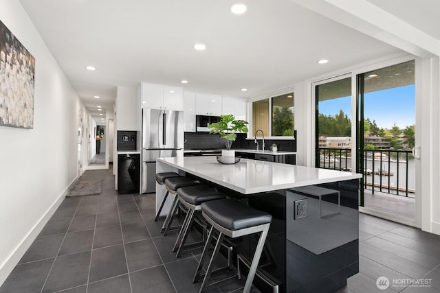 kitchen featuring white cabinets, freestanding refrigerator, baseboards, backsplash, and modern cabinets