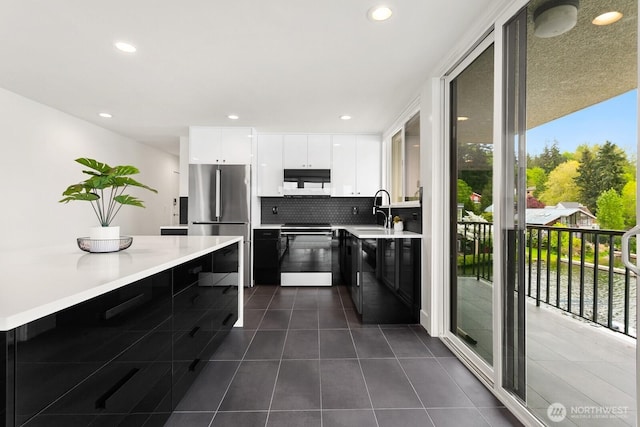 kitchen featuring freestanding refrigerator, white cabinetry, dark tile patterned flooring, a sink, and range