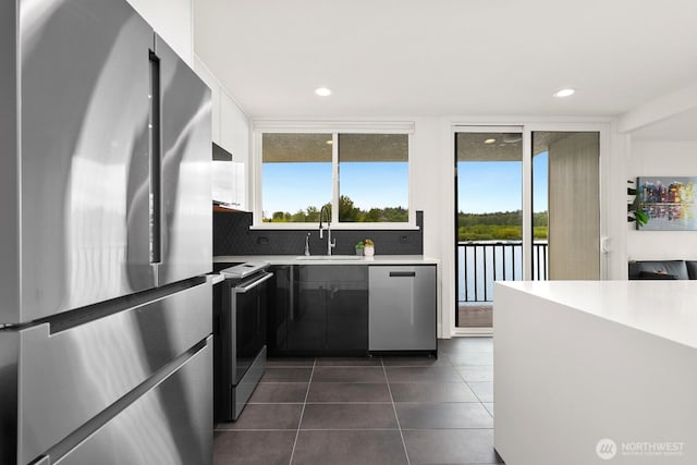 kitchen featuring decorative backsplash, appliances with stainless steel finishes, a wealth of natural light, and a sink