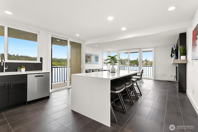 kitchen featuring light countertops, a wealth of natural light, a sink, and dishwasher
