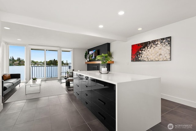 kitchen with light countertops, a center island, recessed lighting, dark tile patterned flooring, and modern cabinets