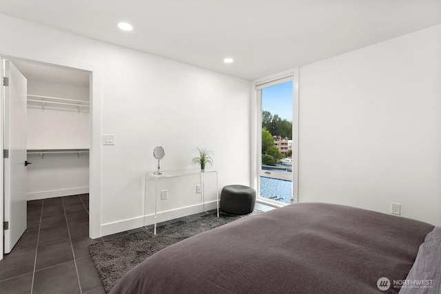 bedroom featuring dark tile patterned floors, baseboards, a spacious closet, and recessed lighting