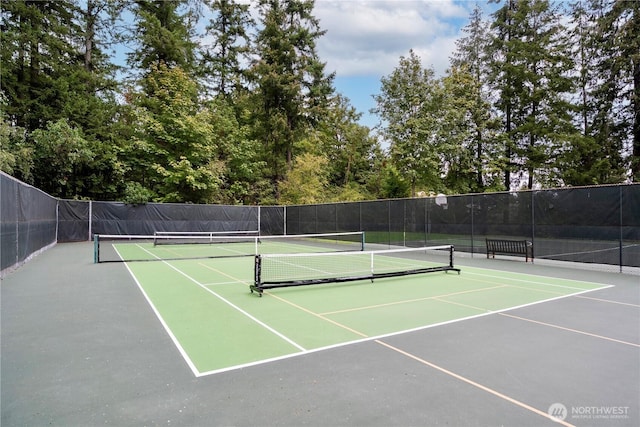 view of tennis court with community basketball court and fence