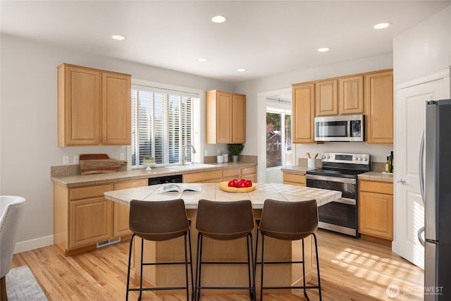 1893 Commodore Ln NW, Bainbridge Island, WA 98110 - kitchen featuring appliances with stainless steel finishes, light brown cabinetry, a sink, a kitchen breakfast bar, and recessed lighting