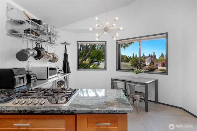 5107 23rd Ave W, Everett, WA 98203 - kitchen with an inviting chandelier, brown cabinetry, light tile patterned flooring, dark stone counters, and stainless steel gas stovetop