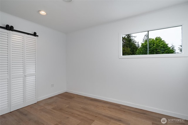 5310 Sunset Ave, Anacortes, WA 98221 - unfurnished bedroom with ornamental molding, wood finished floors, a barn door, recessed lighting, and a closet