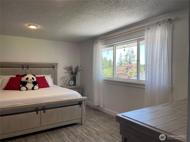 1017 Ballentine St, Raymond, WA 98577 - bedroom featuring baseboards, a textured ceiling, and wood finished floors