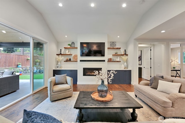 living area featuring a lit fireplace, lofted ceiling, recessed lighting, and wood finished floors