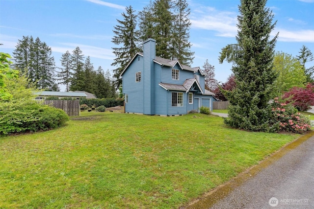 view of side of property with a yard, fence, a chimney, and a garage