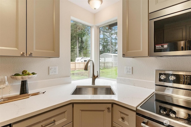 kitchen with light stone counters, a sink, and appliances with stainless steel finishes