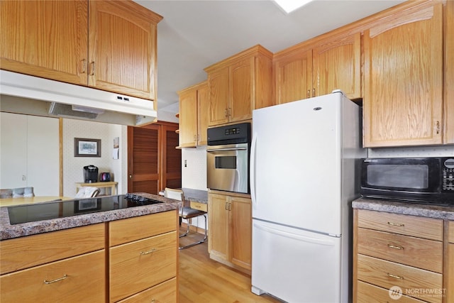 kitchen featuring light brown cabinets, under cabinet range hood, tasteful backsplash, light wood-style flooring, and black appliances