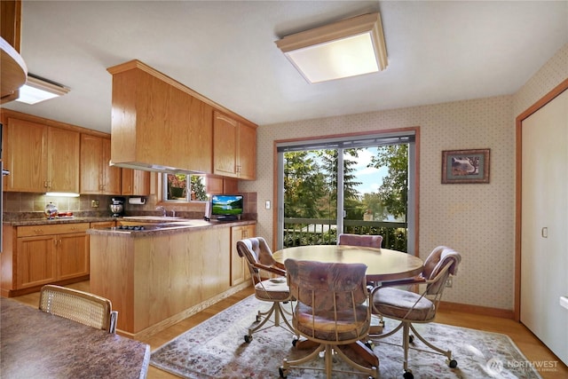 dining space featuring wallpapered walls, baseboards, and light wood-style floors