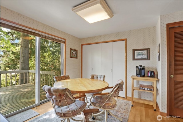 dining space with wallpapered walls and light wood-type flooring