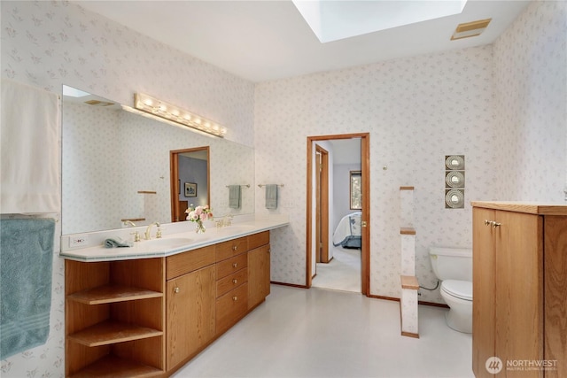 ensuite bathroom with double vanity, a sink, connected bathroom, and toilet