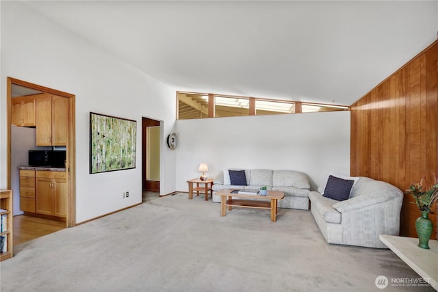living area with wood walls, lofted ceiling, and light carpet