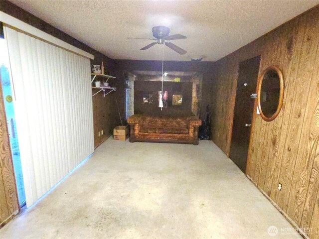 dining area with a ceiling fan, wood walls, and a textured ceiling