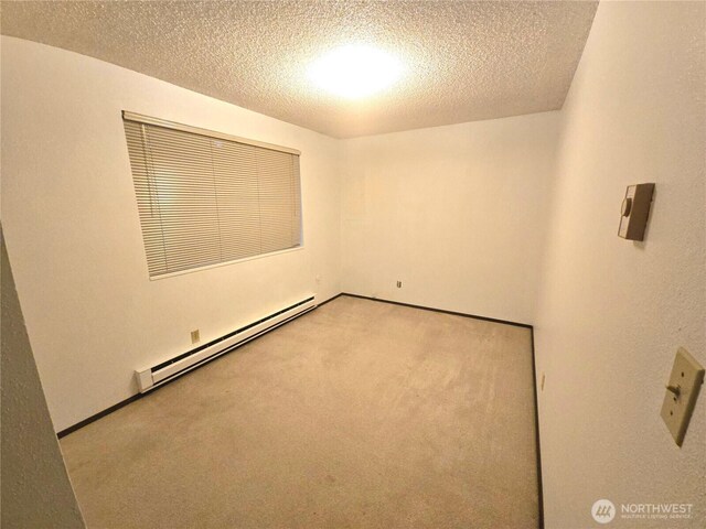 carpeted empty room featuring a textured ceiling and a baseboard radiator