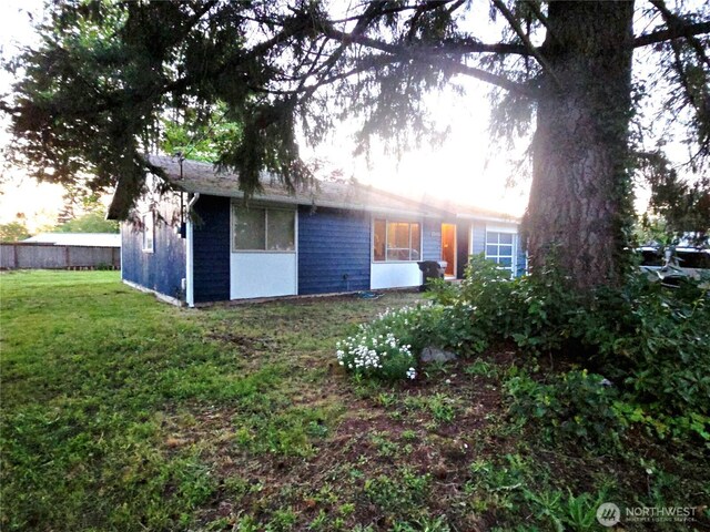 rear view of property featuring fence and a yard