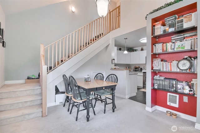 carpeted dining room featuring baseboards, a towering ceiling, and stairway