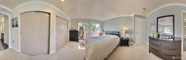 bedroom with baseboards, ornamental molding, multiple closets, and light carpet