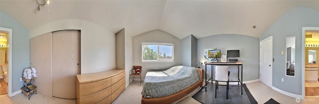 carpeted bedroom with connected bathroom, baseboards, and vaulted ceiling