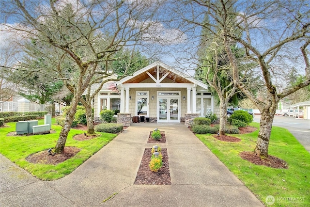 exterior space featuring french doors, stone siding, and a front yard