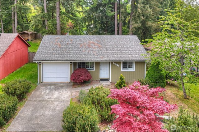 view of front of house with roof with shingles, an attached garage, and driveway