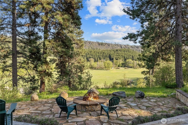 view of patio / terrace featuring a fire pit and a wooded view