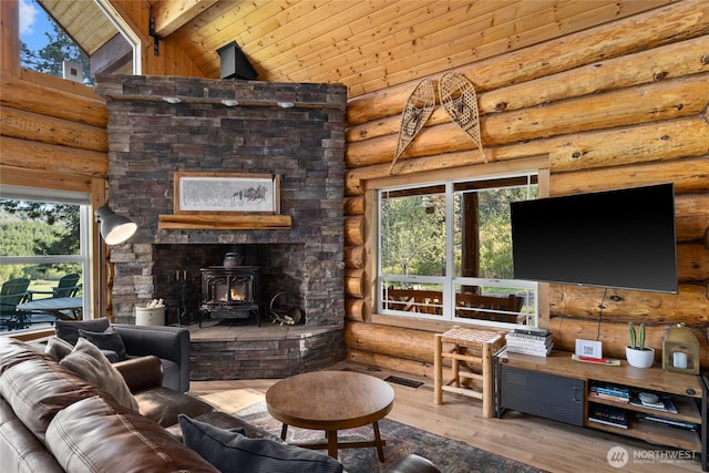 living room featuring log walls, a wood stove, beam ceiling, wood ceiling, and plenty of natural light