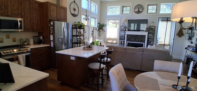 kitchen with a kitchen island, a kitchen bar, light countertops, dark wood finished floors, and stainless steel appliances