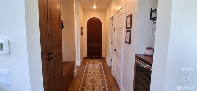 hall with arched walkways, wine cooler, and dark wood-style floors
