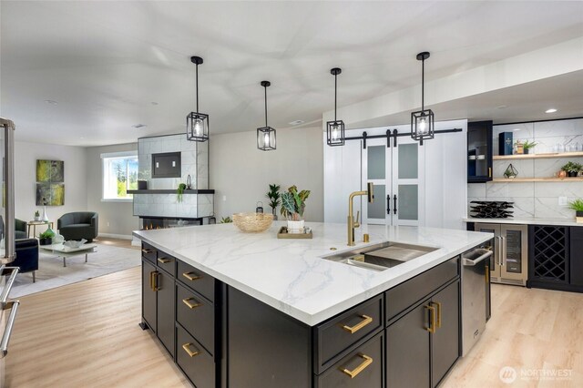 5732 Halls Lake Way, Lynnwood, WA 98036 - kitchen featuring decorative backsplash, a barn door, a sink, light wood finished floors, and open floor plan