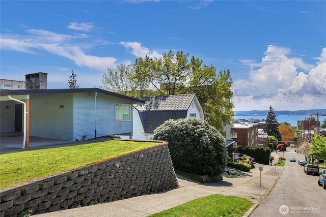 view of property exterior featuring a lawn and a water view