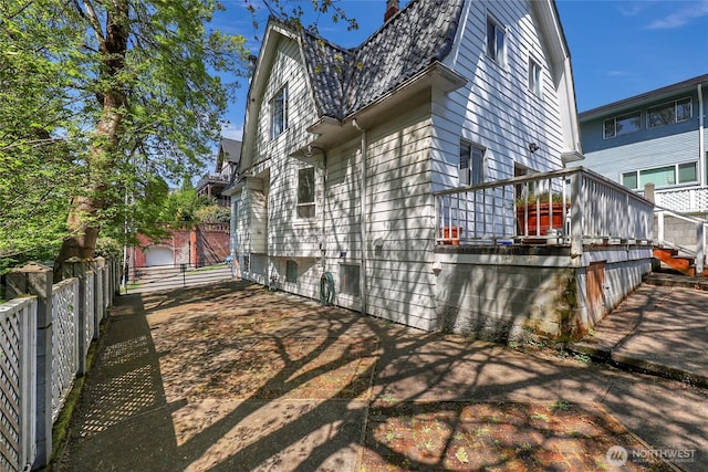 view of side of home with a gambrel roof and fence