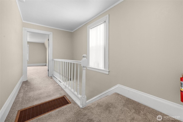 hall with carpet flooring, ornamental molding, baseboards, and an upstairs landing