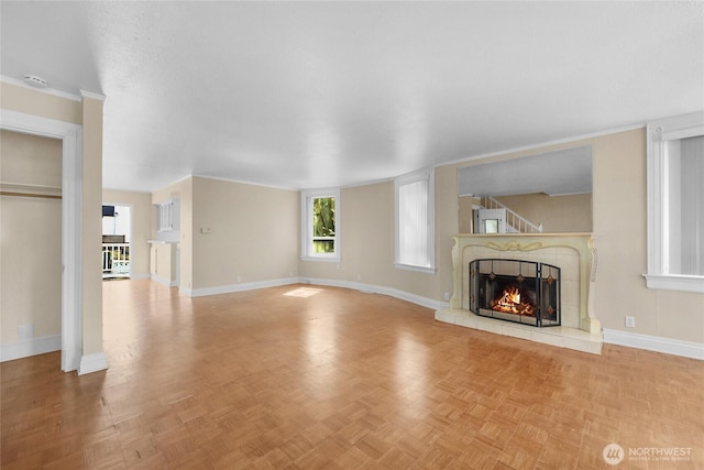 unfurnished living room featuring a tile fireplace and baseboards