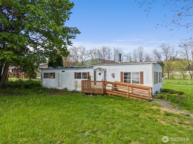 back of property featuring a lawn and a wooden deck