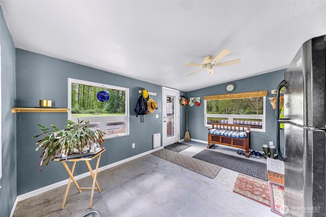 foyer entrance with baseboards, ceiling fan, a textured ceiling, concrete floors, and vaulted ceiling