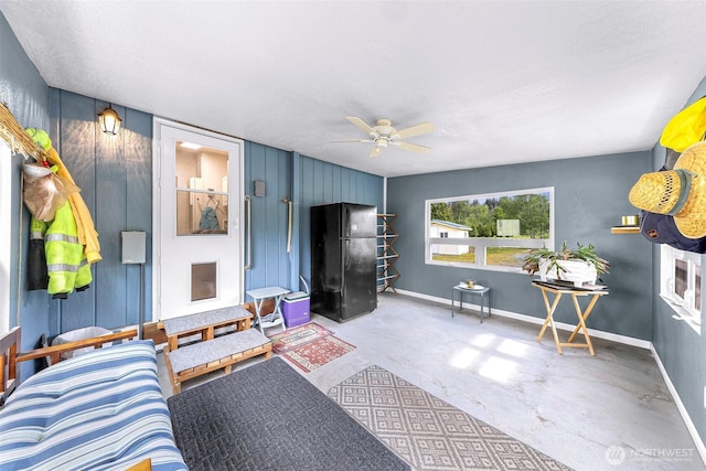 living area with baseboards, ceiling fan, and unfinished concrete flooring