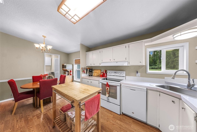 kitchen with white appliances, light countertops, a sink, light wood finished floors, and a notable chandelier