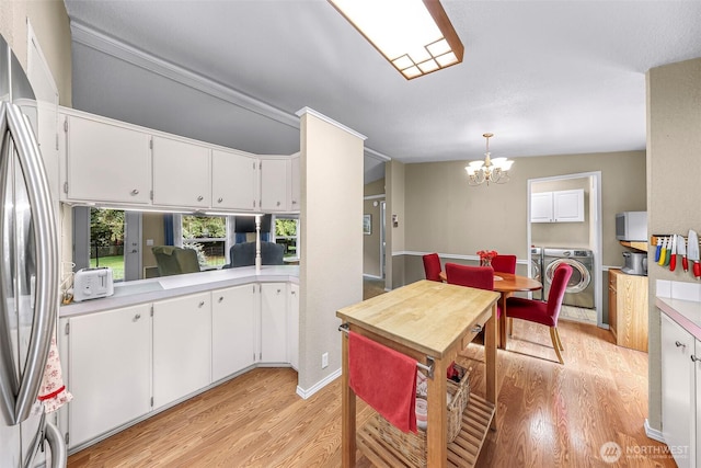 kitchen with a notable chandelier, separate washer and dryer, freestanding refrigerator, white cabinetry, and light wood-type flooring