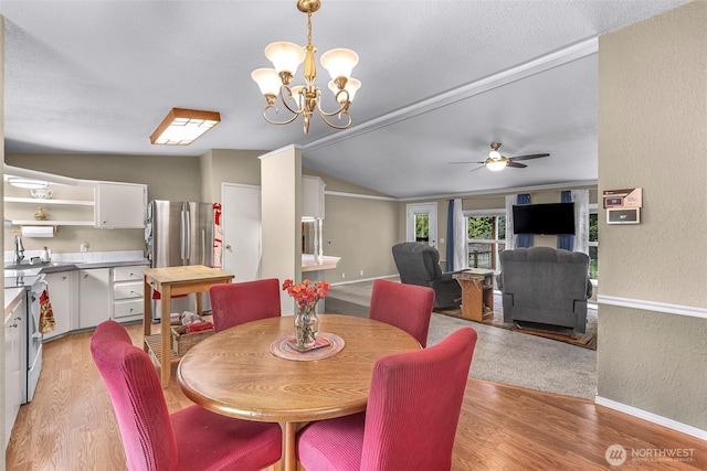 dining space with a textured wall, baseboards, light wood-style flooring, ceiling fan with notable chandelier, and vaulted ceiling